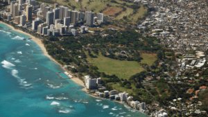 A picturesque view of Kahala, Hawaii, featuring golden sandy beaches, clear turquoise waters, and lush greenery with luxurious beachfront homes in the background.